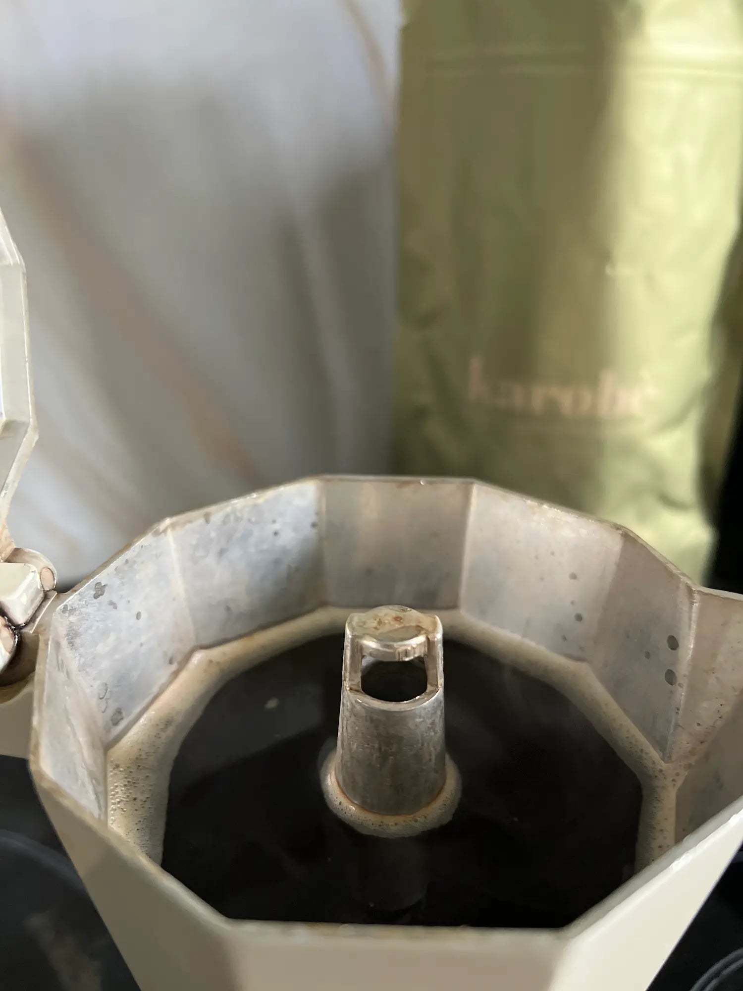 Brewing Karobe roasted carob in a moka pot filter basket, demonstrating preparation for a rich, dark espresso alternative.