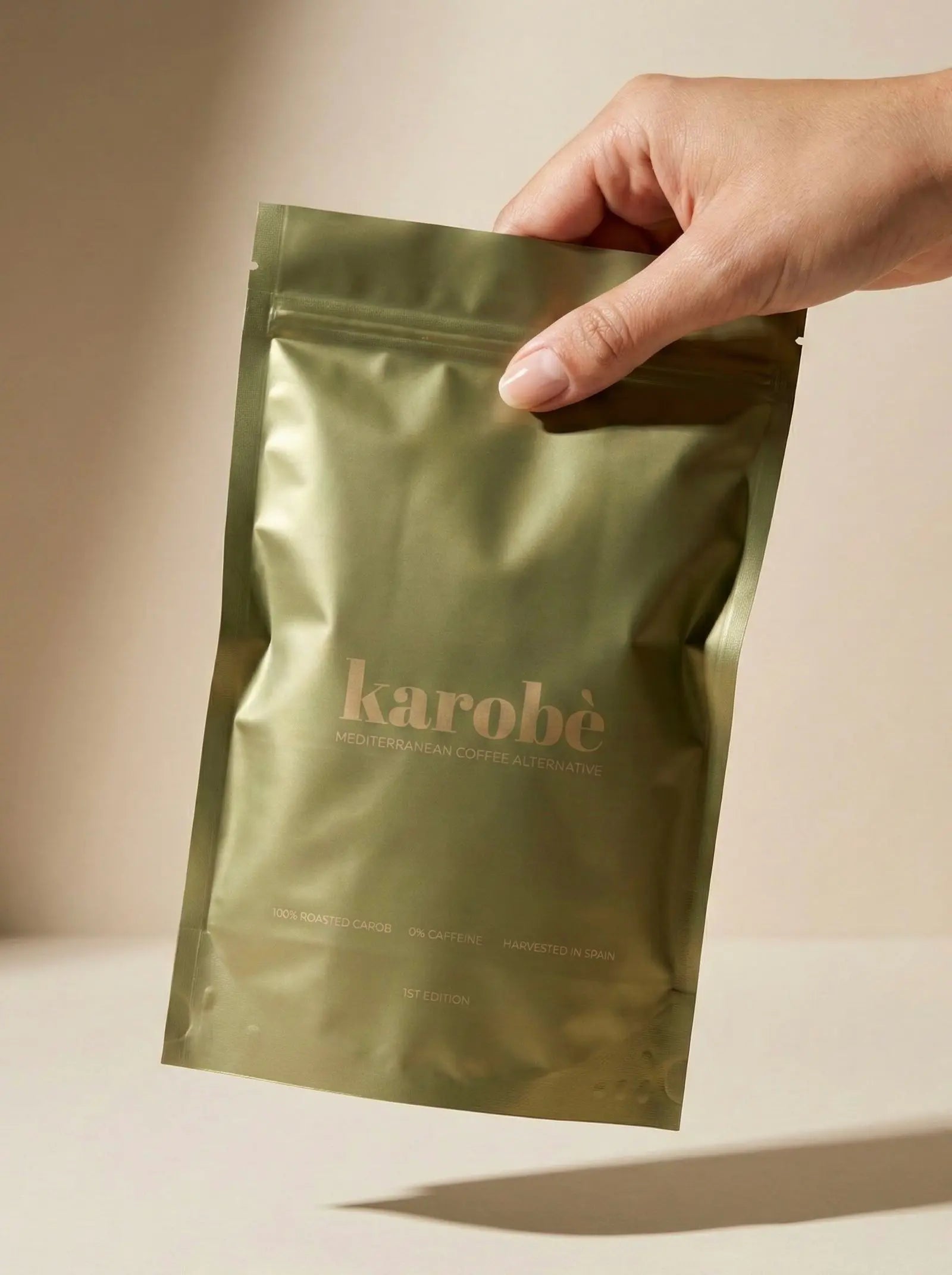 Hand holding the Karobe roasted carob powder package, showing the convenient size.